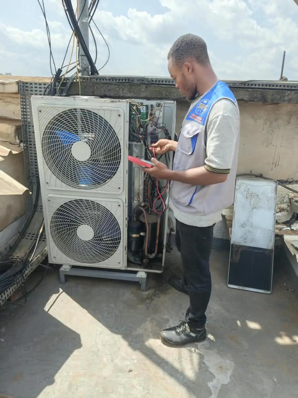 Technicien SOS Frigoriste contrôlant un groupe de climatisation sur un toit