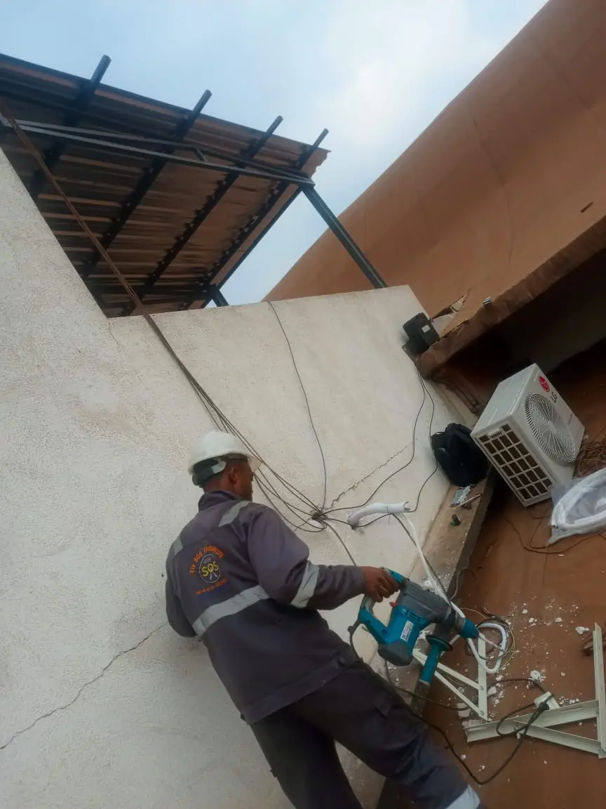 Technicien SOS Frigoriste perçant le mur pour poser une clim